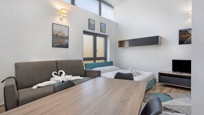 Et moderne hotelværelse med sofa, seng, træbord og fjernsyn.