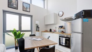Una cocina moderna con comedor, un ventanal grande y una planta en maceta.