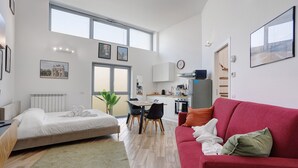 Un apartamento moderno con cama, sofá rojo, comedor y cocina.