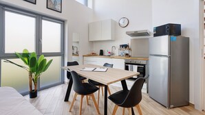 Una cocina moderna con comedor, un refrigerador y un reloj en la pared.