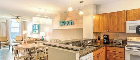 A modern kitchen with granite countertops, wooden cabinets, a built-in dishwasher, and a microwave.