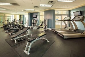 Ein Fitnessstudio mit Laufbändern, Crosstrainern und Gewichtbänken.
