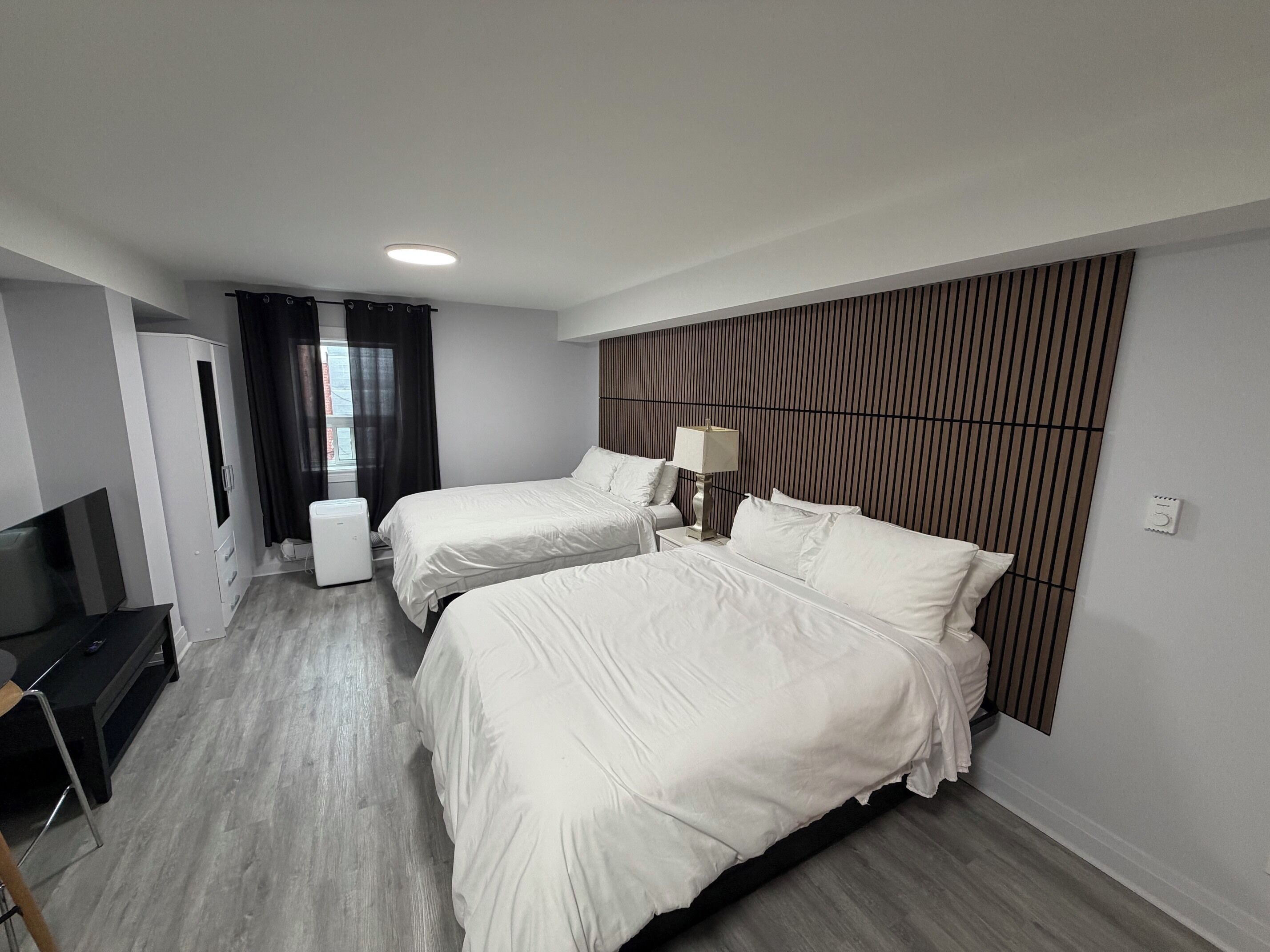 Habitación de hotel con dos camas, televisor, escritorio y armario.
