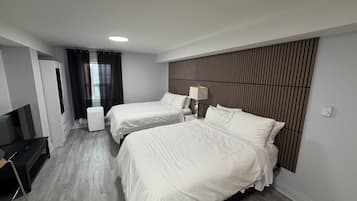 Habitación de hotel con dos camas, televisor, escritorio y armario.