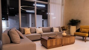 A modern living room with a sectional sofa, a wooden coffee table, a yellow armchair, and a large window. - Apartamento de lujo Cartagena Beach, Cartagena de indias -Colombia (Cartagena de Indias)