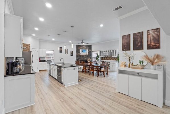 A modern kitchen with white cabinetry, a central island, and a dining area with wooden chairs.