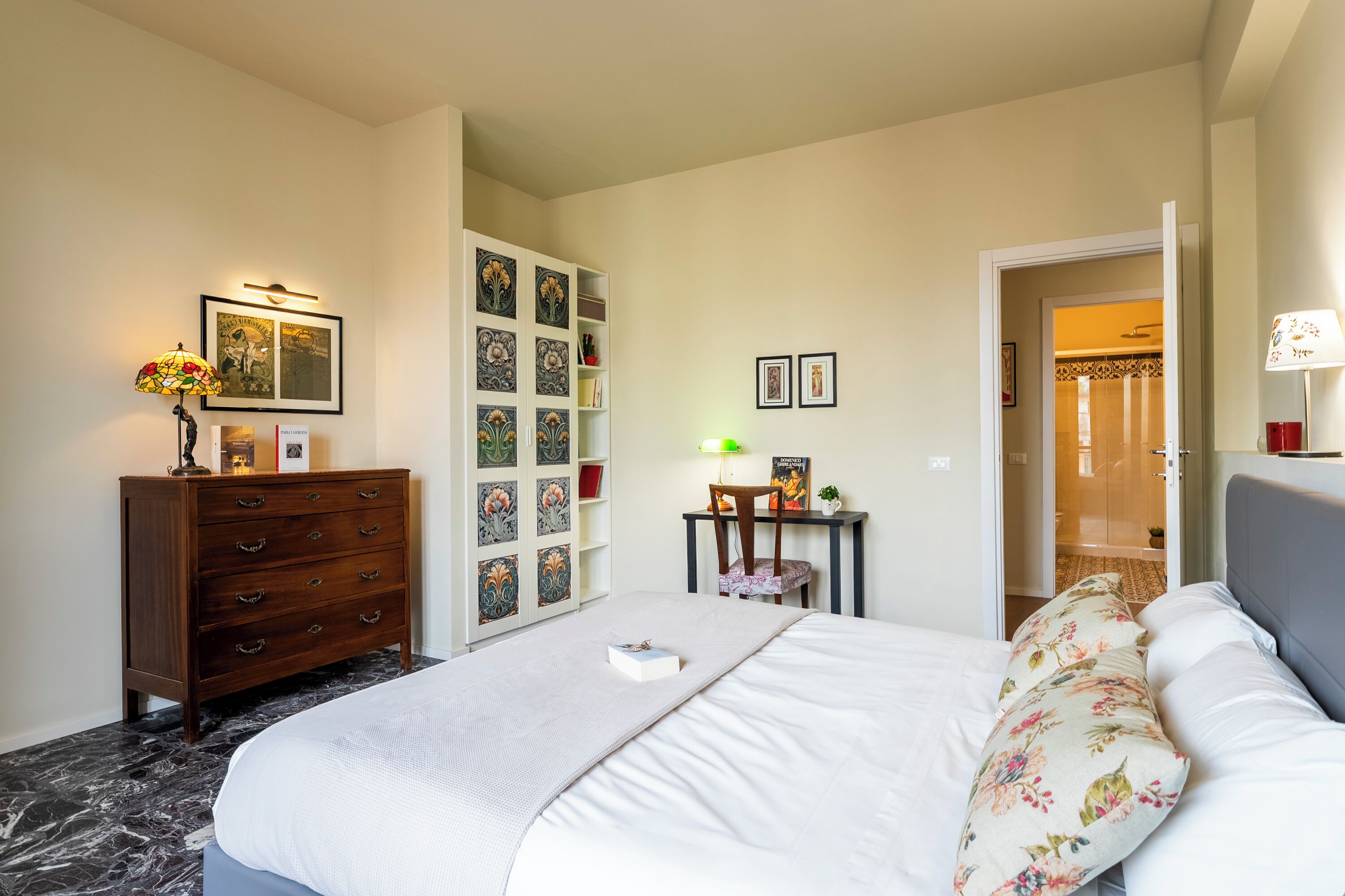 Un dormitorio con cama, cómoda y pared decorada con cuadros.