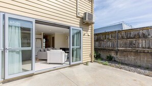 Une maison moderne dotée d’une porte-fenêtre coulissante qui donne sur un espace de vie comprenant un canapé et un téléviseur.