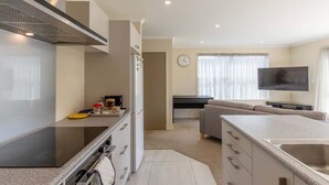 Une cuisine moderne équipée d’une cuisinière intégrée, d’un réfrigérateur et d’un four à micro-ondes. On y trouve également un coin repas avec un canapé et un téléviseur à écran plat.