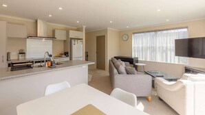 Un appartement moderne comprenant une cuisine, un coin repas, un salon et un téléviseur.