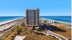A high-rise hotel with multiple floors, a beach view, and a parking area. - Portofino Island Resort 1-1502 (Pensacola Beach)
