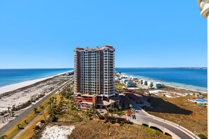 A high-rise hotel with multiple floors, a beach view, and a parking area. - Portofino Island Resort 1-1502 (Pensacola Beach)