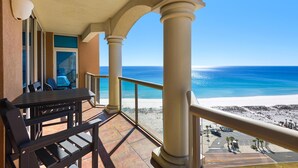 A balcony with a view of the beach and ocean, featuring a table and chairs, and a railing. - Portofino Island Resort 1-1502 (Pensacola Beach)