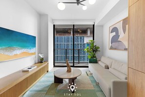 Ein modernes Wohnzimmer mit großem Fenster, einer Couch, einem Couchtisch und einem Gemälde.