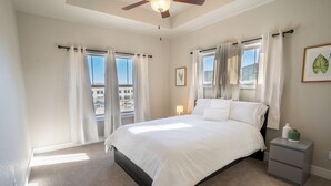 A bedroom with a large bed, two bedside tables, a ceiling fan, and a window with curtains. - Escape to the heart of Colorado! (Loveland)
