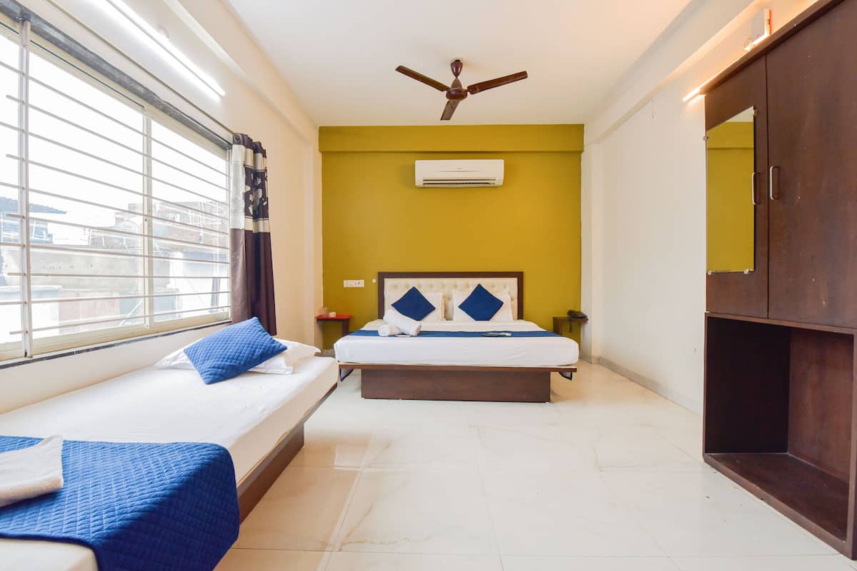 A hotel room with two beds, a ceiling fan, an air conditioning unit, and a large wardrobe.