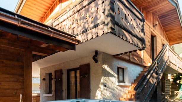 A wooden cabin with a hot tub, wooden exterior, and a balcony. - Jacuzzi in the Heart of the Village – “L'Ours” Apartment with Private Terrace and Wi-Fi (Châtel)
