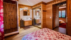 A wooden room with a bed, a mirror, a sink, and a wardrobe. - Jacuzzi in the Heart of the Village – “L'Ours” Apartment with Private Terrace and Wi-Fi (Châtel)
