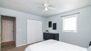 A bedroom with a bed, a dresser, a ceiling fan, a door, and a window. - 2BR I 4 mins to FargoDome, Free Pking, Queen x 2 (Fargo)
