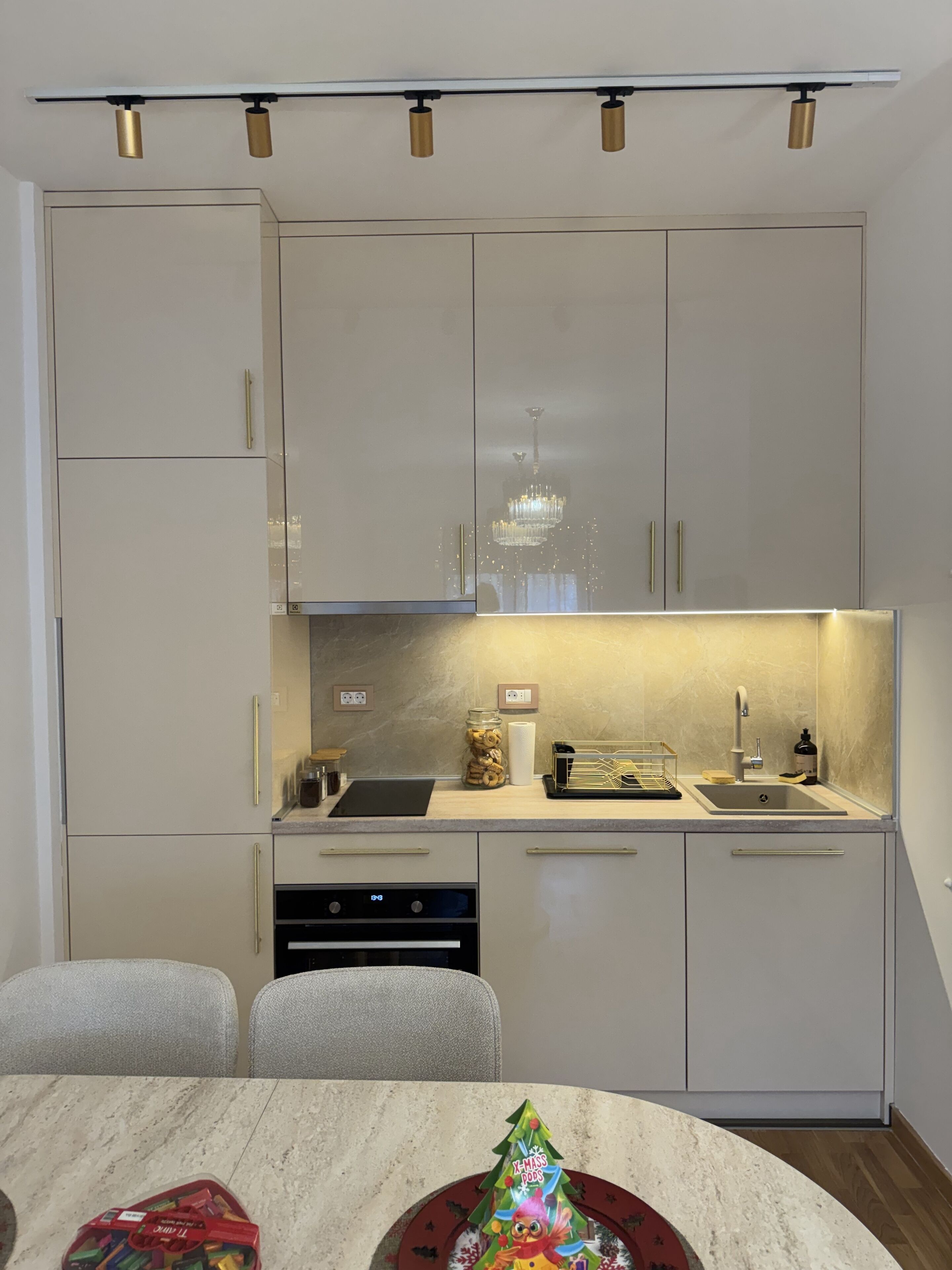 A modern kitchen with a central island, built-in appliances, and a chandelier.