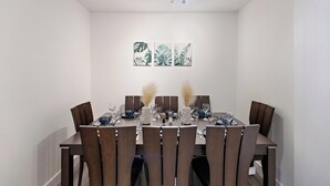 Uma sala de jantar com uma mesa retangular posta para seis pessoas, rodeada por seis cadeiras.