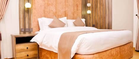 A neatly made bed with white and beige bedding, a wooden headboard, and bedside lamps.