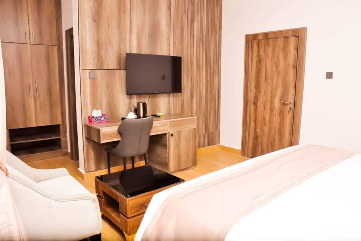 Une chambre d’hôtel avec une armoire en bois, un bureau avec une chaise, une télévision et un lit.