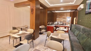 Un restaurante con piso de mármol, detalles de madera y un sofá tapizado en verde.