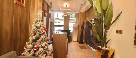 A hotel lobby with a Christmas tree, seating area, and a reception desk.