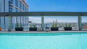 A rooftop pool with a clear view of the cityscape, surrounded by potted plants and seating areas. - Kenect 1310 (Phoenix)
