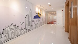 Corridoio di un hotel con un murale che raffigura un panorama urbano, un cartello con la scritta 'letto da sogno' e una porta in legno sulla destra.