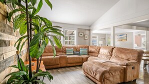 Un salón amplio con un sofá grande de cuero, una mesa de centro de madera y una planta en maceta.