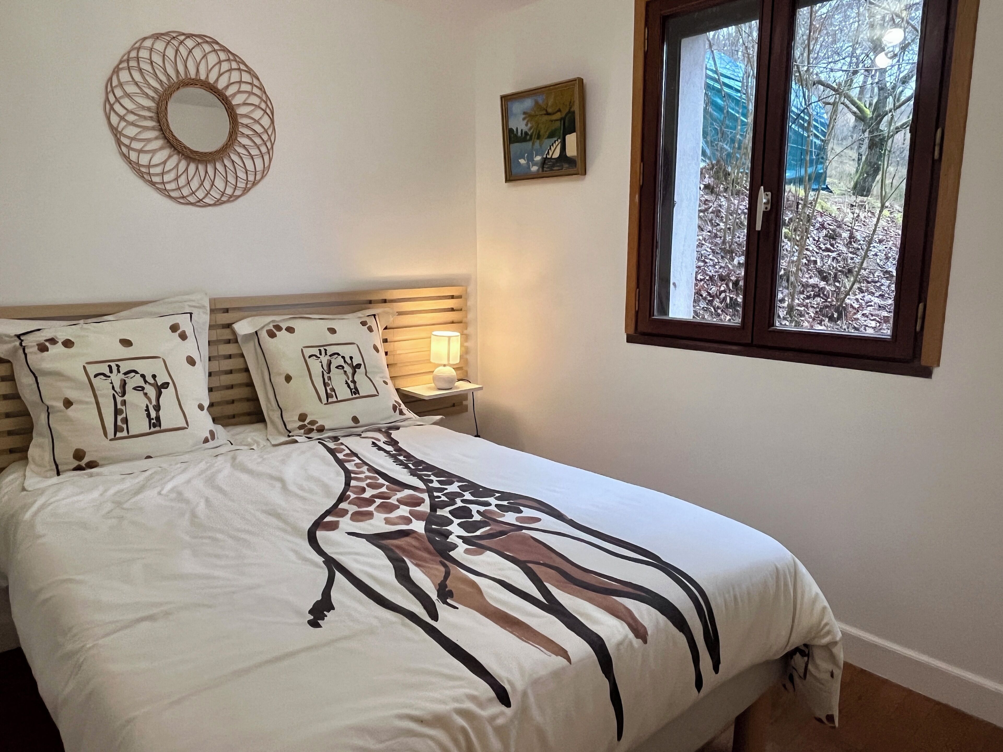 Un lit bien fait, agrémenté d’un coussin à motifs de girafe et d’une couvre-lit à rayures de girafe.