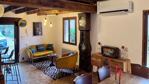 A spacious living room with a high ceiling, a wooden staircase, a large clock, and a vintage radio.