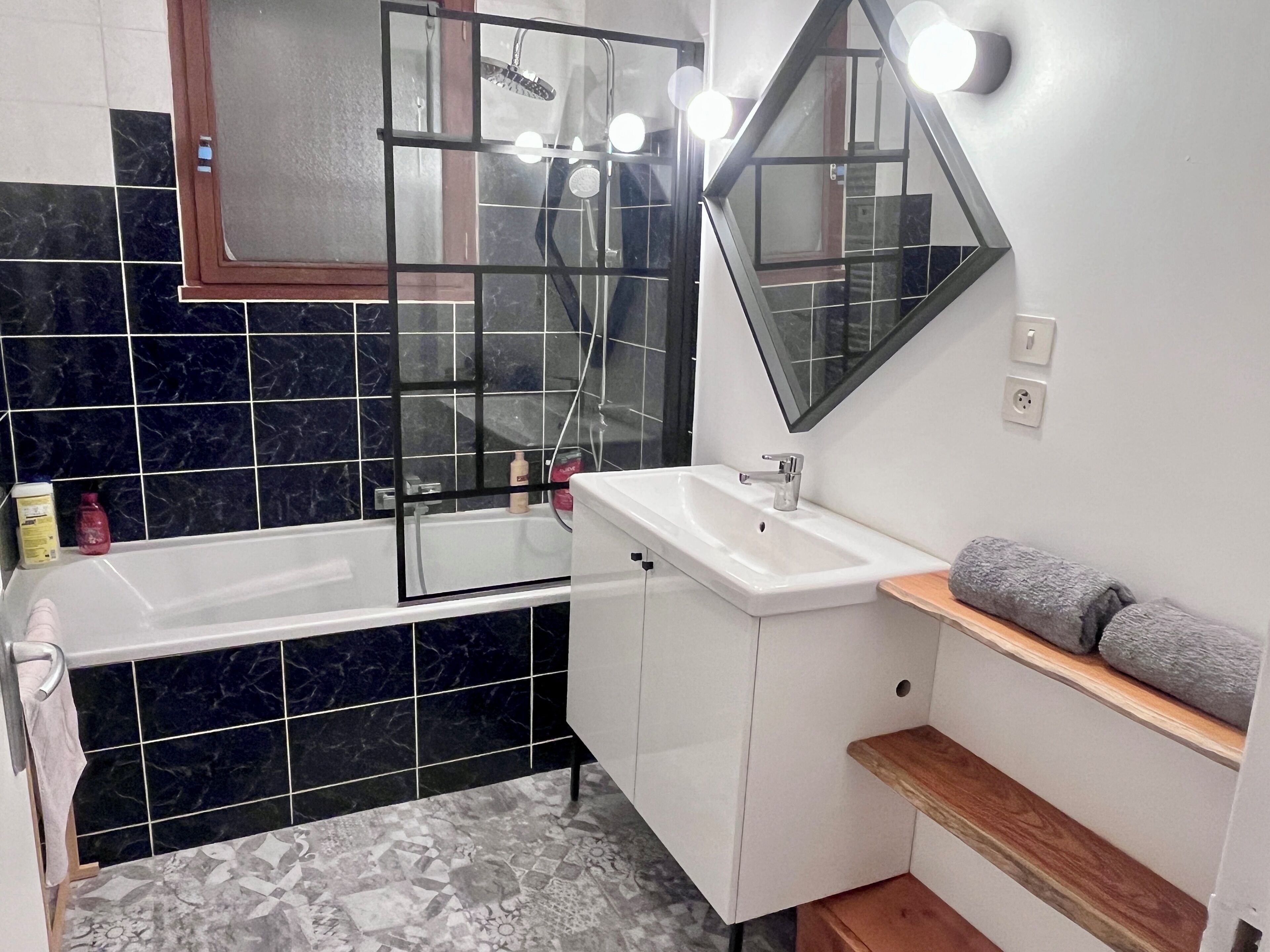 Ein modernes Badezimmer mit einer Duschkabine, einem weißen Waschbecken und einem Spiegel darüber.