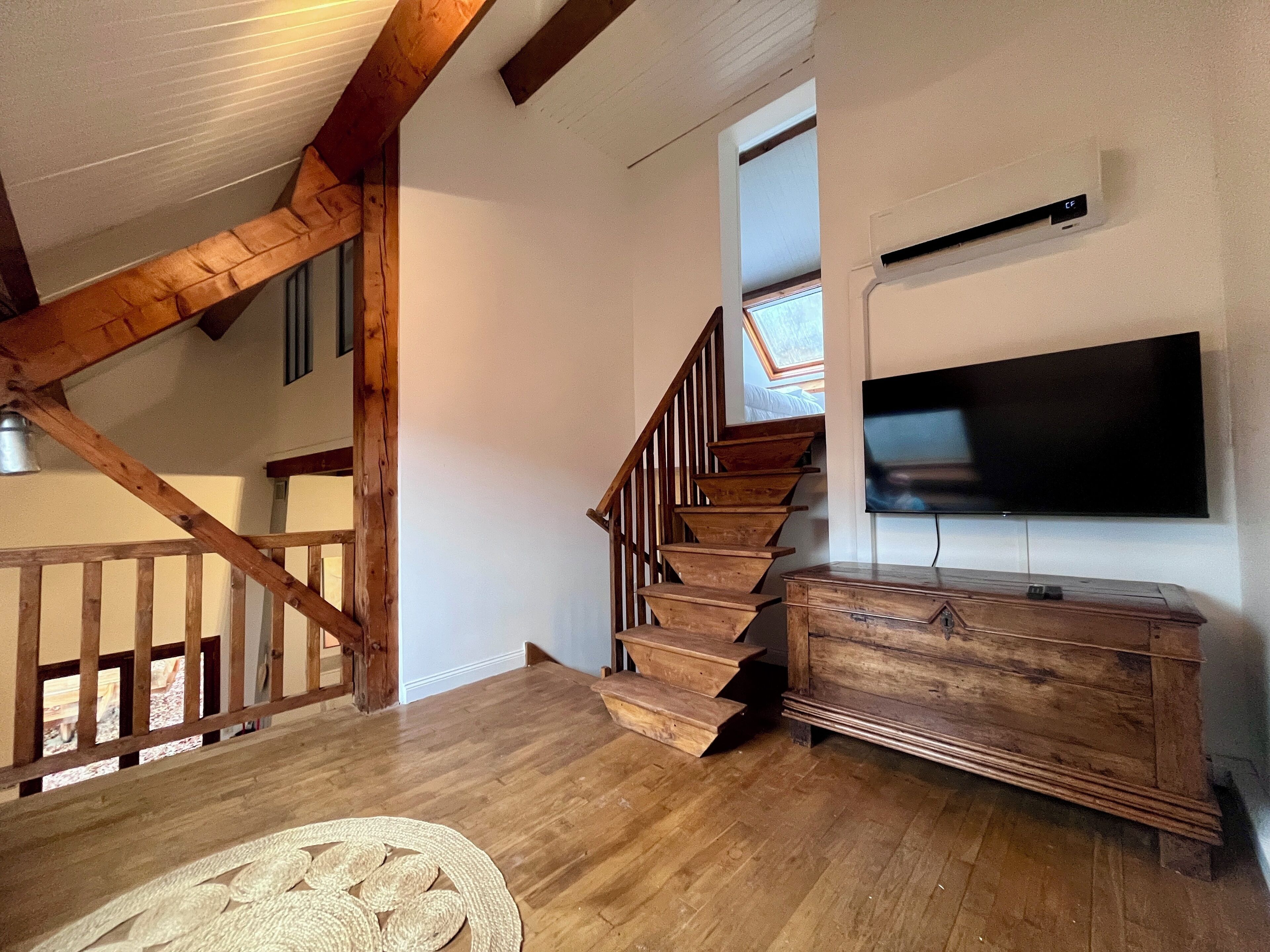 A wooden staircase with a TV mounted on the wall above it.