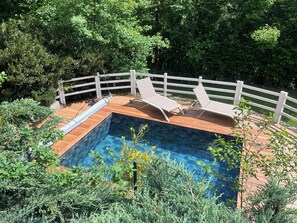 A swimming pool with a wooden deck, surrounded by a white fence, and lush greenery in the background. - Haven of peace in the heart of nature with heated swimming pool - Vallée de la Sioule (Saint-Gervais-d'Auvergne)