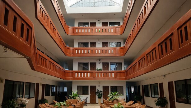 A multi-level atrium with wooden railings, potted plants, and wicker furniture. - Collection O Night Bazaar Chiangmai (Chiang Mai)