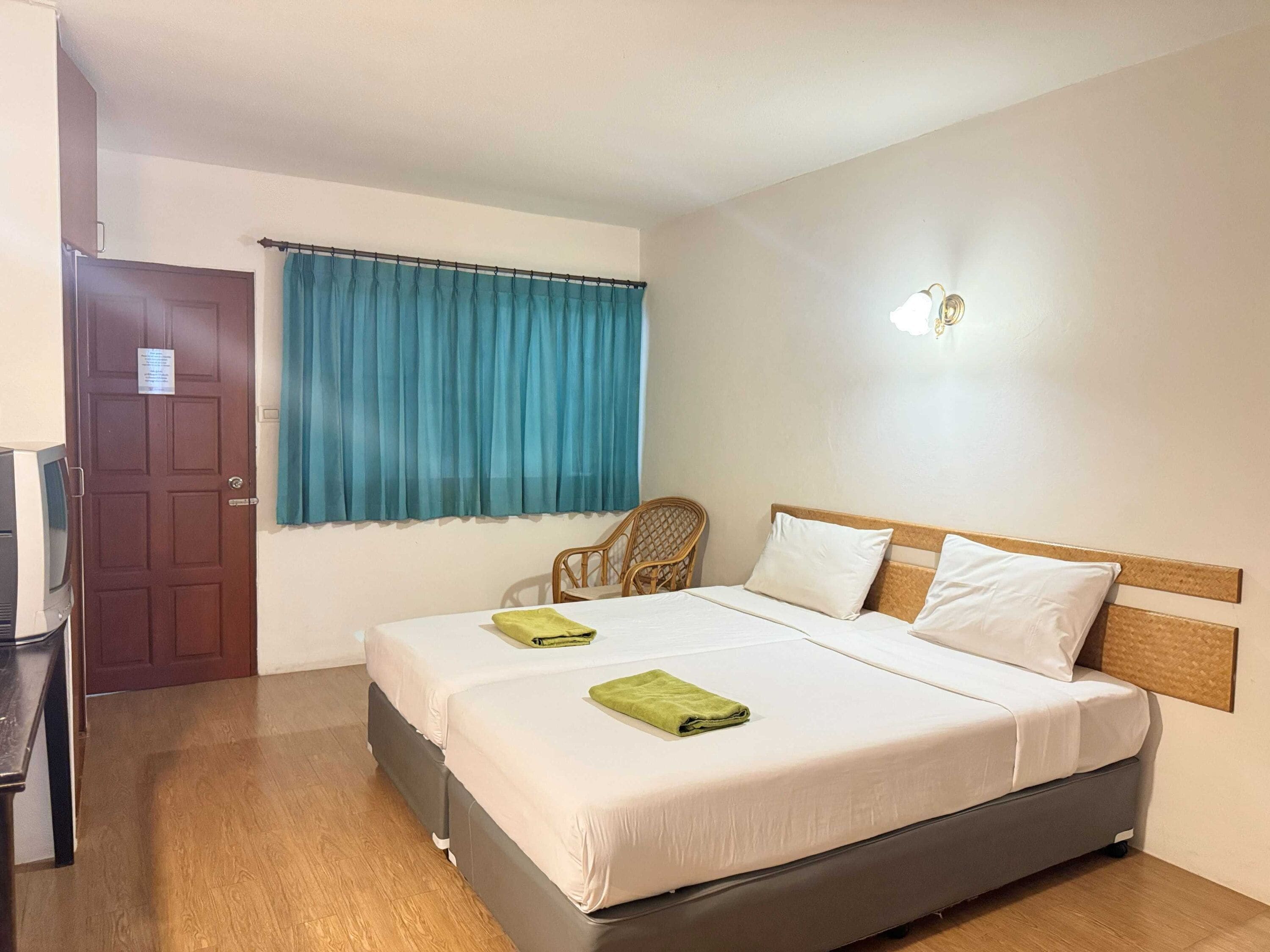 Una habitación de hotel con una cama, una silla, un televisor y una puerta.