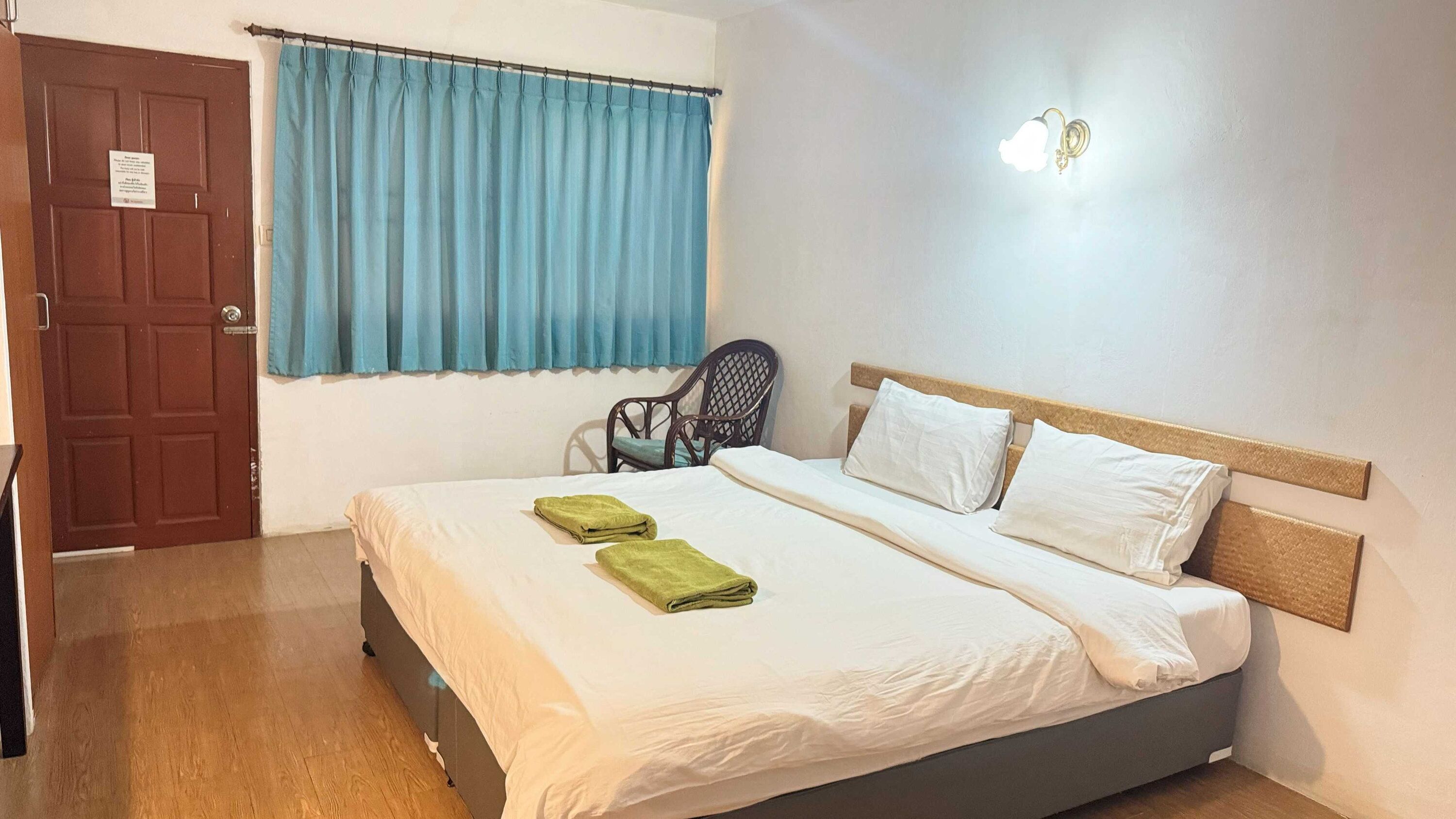 Une chambre d’hôtel avec un lit, une chaise et une fenêtre avec des rideaux.
