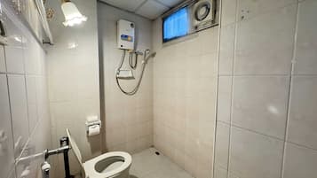 A small, tiled bathroom with a toilet, a hand dryer, and a wall-mounted heater.