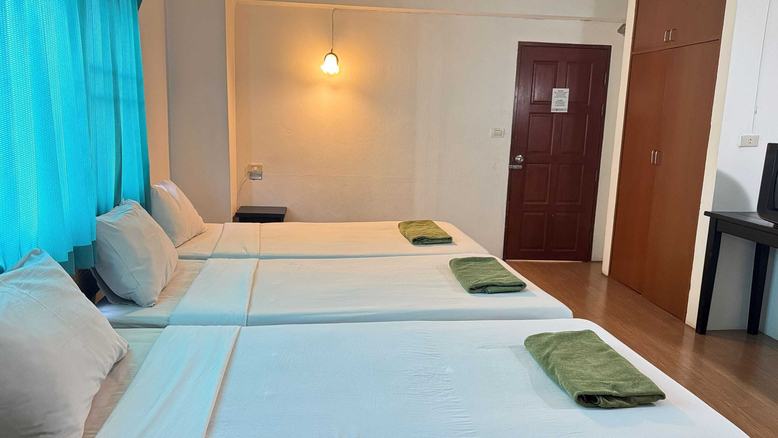 Ein Hotelzimmer mit zwei Betten, einem Schreibtisch, einem Fernseher und einer Tür.