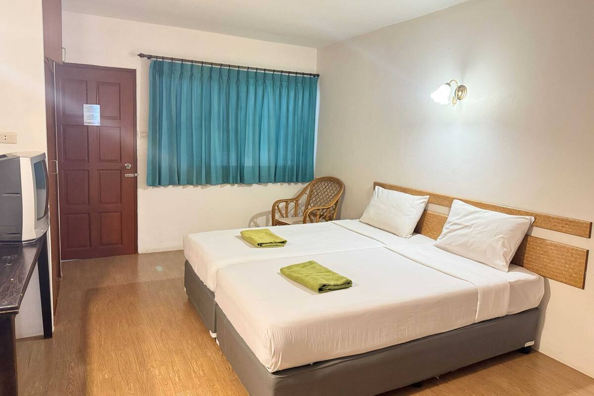 Una habitación de hotel con una cama, una silla, un televisor y una puerta.