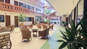 A hotel courtyard with wicker furniture, potted plants, and a tiled floor. - Collection O Night Bazaar Chiangmai (Chiang Mai)