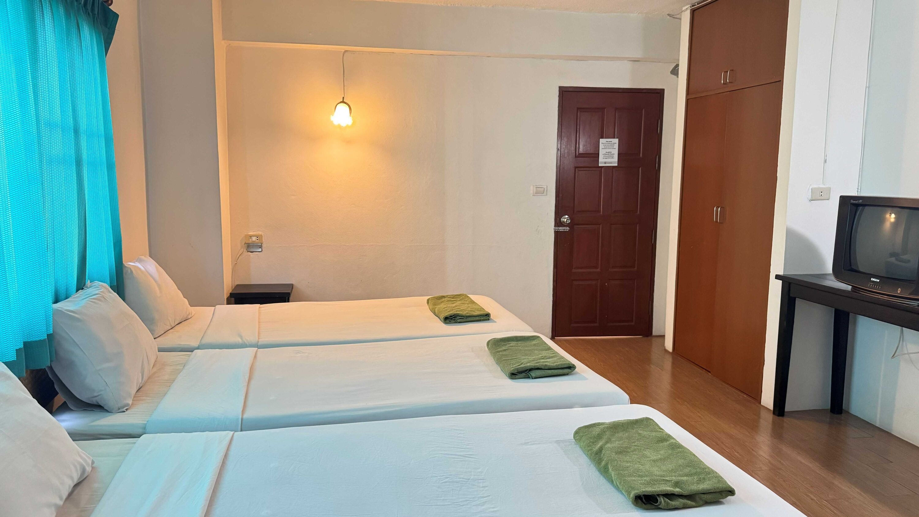 Una habitación de hotel con dos camas, un televisor y una puerta.