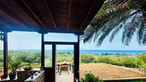 Une terrasse couverte avec vue sur la mer et la verdure.