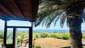 Un espace extérieur abrité offrant une vue sur la mer et la verdure.
