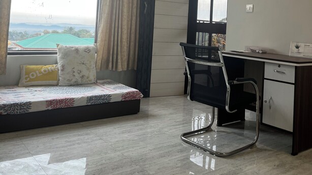 Une pièce comprenant un lit, un bureau et une chaise. Il y a une fenêtre avec des rideaux, un ventilateur de plafond et un luminaire fixé au mur.