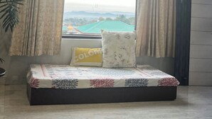 Une chambre avec un lit, une fenêtre avec des rideaux, un ventilateur de plafond et une vue sur un paysage lointain.
