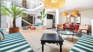 Amplia sala de estar con techo alto, una escalera y un comedor con sillas y mesa.